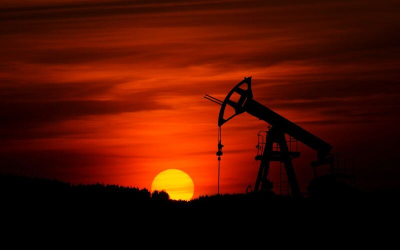 Oil pump jack silhouetted against a red sunset